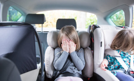 Drie kinderen in autostoelen op de achterbank